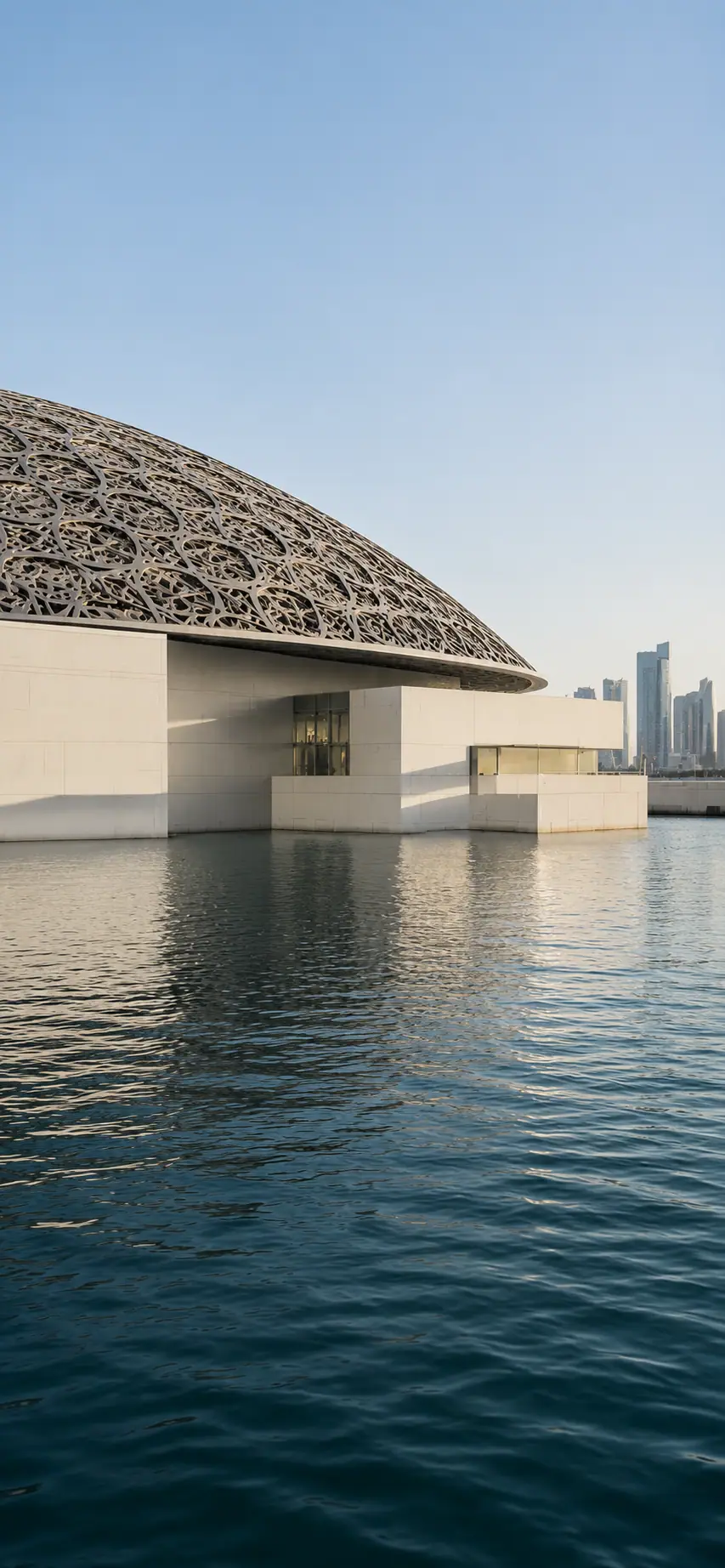 The Louvre Abu Dhabi over the water with the city skyline beyond